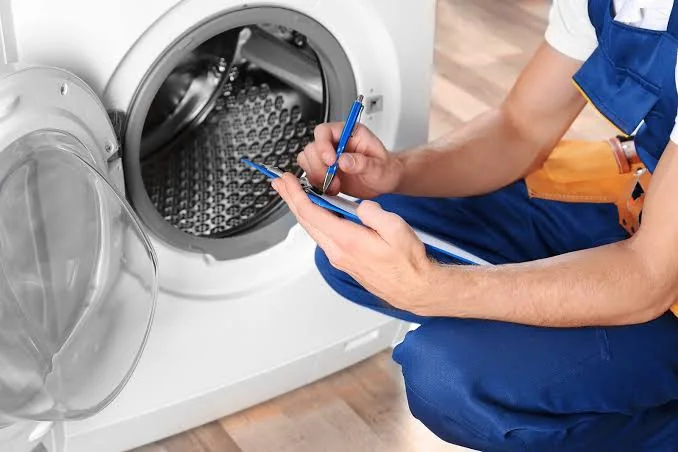 Technician documenting a washing machine issue during an appliance service visit