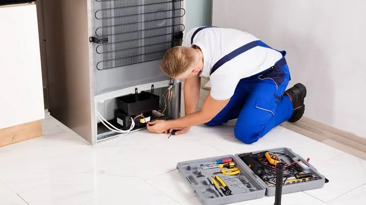 Technician evaluating the rear cooling system of a household freezer